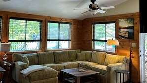 Un salon confortable avec un canapé d’angle, une table basse et un ventilateur de plafond.