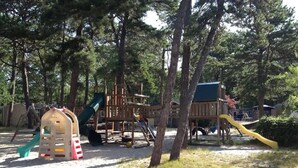 Ein Spielplatz mit Rutsche, Klettergerüsten und Sandkasten.