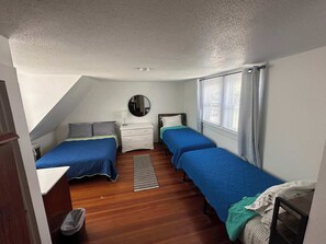 Ein Schlafzimmer mit zwei Betten, einem Schminktisch, einem Spiegel und einem Fenster mit Vorhängen.