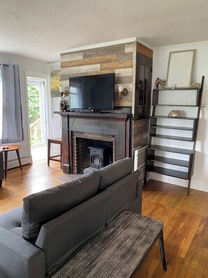 A living room with a fireplace, a television, a sofa, and a staircase. - Spacious 4 Bedroom House on Campground/Retreat! (Yarmouth)