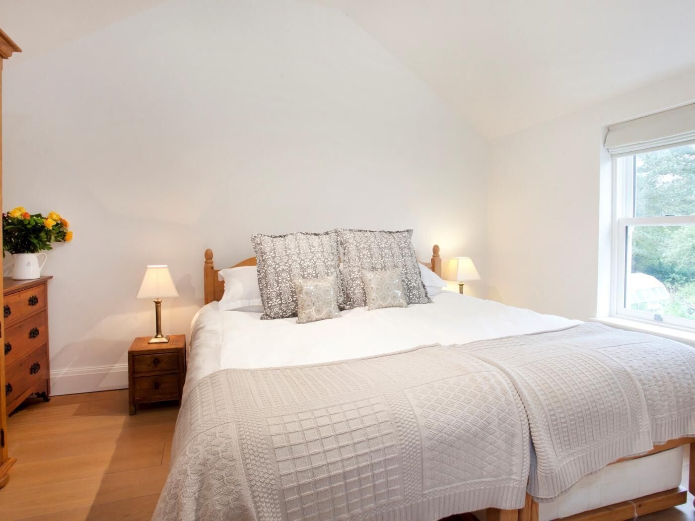 A bedroom with a bed, bedside tables, a dresser, and a window.