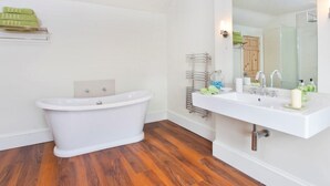 A bathroom with a freestanding bathtub, a white sink with a large mirror, and a towel rack. - 1 Bed in York (oc-g0043) (Holtby)