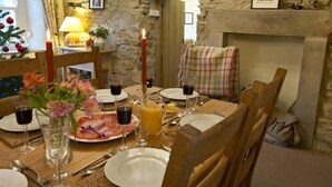 A dining table set with plates, glasses, and cutlery, a candle, and a Christmas tree in the background. - 4 Bed in Kettlewell (oc-g0041) (Starbotton)