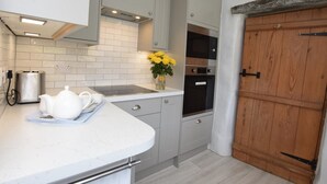 A kitchen with grey cabinets, a white countertop, a toaster, a kettle, and a vase with yellow flowers. - 4 Bed in Kettlewell (oc-g0041) (Starbotton)