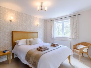 Ein Schlafzimmer mit einem Bett, Nachttischen, einem Fenster mit Vorhängen und einer an der Wand montierten Lampe.