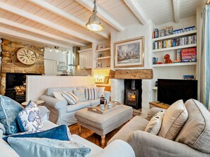 Ein gemütliches Wohnzimmer mit Kamin, Bücherregal und einer Wanduhr.