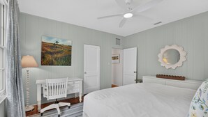 Una camera da letto con un letto, una culla, una ventola a soffitto, uno specchio montato a parete e un quadro.