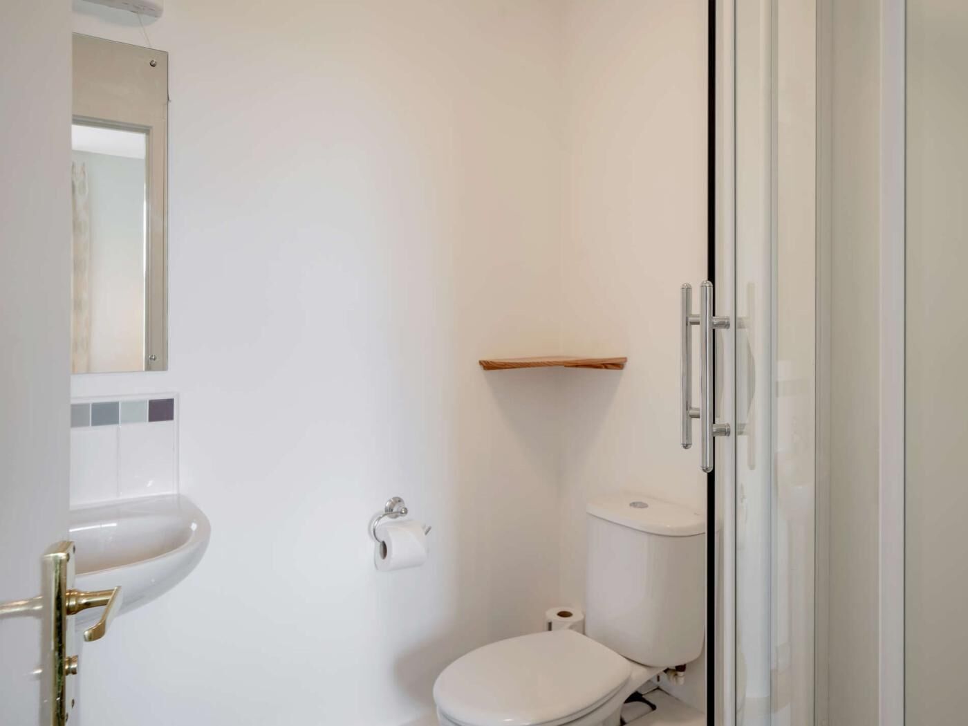 Ein kleines, weißes Badezimmer mit Toilette, Waschbecken und Spiegel.