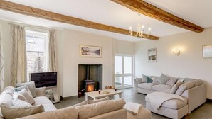A living room with a fireplace, sofas, a television, and a chandelier. - 8 Bed in Cockermouth (oc-82453) (Blindcrake)