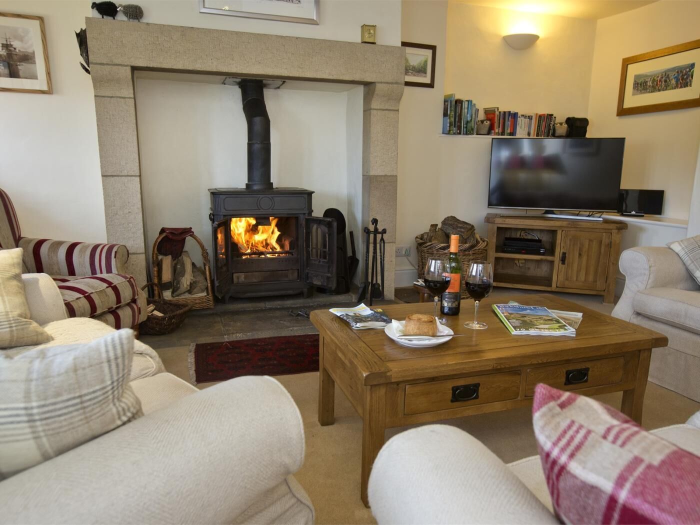 A cozy living room with a fireplace, sofas, a coffee table, and a television.