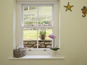 Ein Fenster mit einer Steinwand, einem Korbwäsche und zwei Blumentöpfen.
