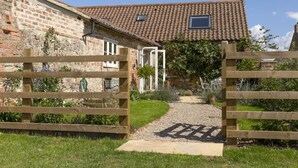 Una casa rústica con techo de tejas, fachada de ladrillo y portón de madera.