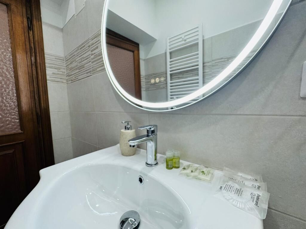 Un bagno con un lavandino bianco, uno specchio e articoli da toilette.