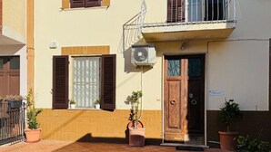 A building with a tiled patio, a wooden door, and potted plants. - Villa Matilde (Pisa)