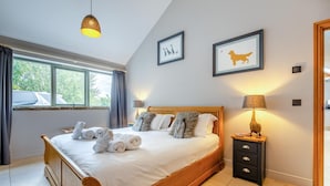 Un dormitorio con cama de madera, una mesita de noche con lámpara y cuadros en la pared.