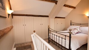 A bedroom with a bed, a white railing, and a sloped ceiling with wooden beams. - 1 Bed in Ripley (oc-g0127) (Kirkby Malzeard)