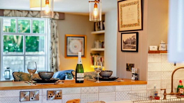 A kitchen with a large island, wine glasses, a bottle of wine, and a loaf of bread. - 1 Bed in Pickering (oc-g0120) (Rosedale Abbey)