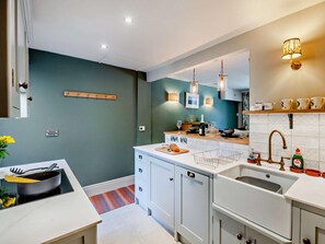A modern kitchen with white cabinets, a central island, pendant lighting, and a backsplash.