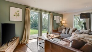 Ein Wohnzimmer mit Fernseher, Sofa, Couchtisch und Bildern an den Wänden.
