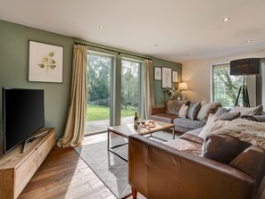 A living room with a TV, sofa, coffee table, and artwork on the walls. - 3 Bed in Otley (oc-g0176) (Norwood)
