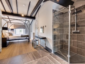 A modern bedroom with a curved bed, a glass shower enclosure, and a wooden floor. - 6 Bed in Richmond (oc-g0178) (Gilling West)