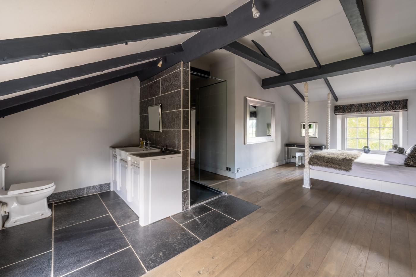 A modern loft bedroom with a large window, a built-in bed, and a separate bathroom with a vanity.