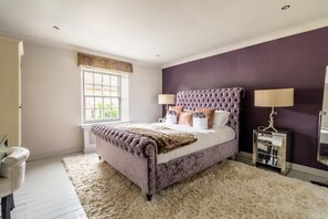 Quarto com cama grande, mesa de cabeceira, abajur e janela com vista.
