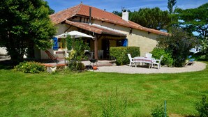 Een huis met een terras, buitenmeubels en een barbecueplaats.