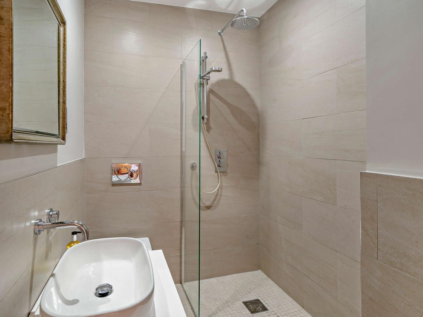 Une salle de bain avec une douche à parois de verre, un lavabo blanc et un miroir.