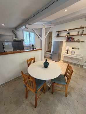A modern kitchen with a central island, wooden chairs, and a round table with a vase. - "Gege's Cottage" House with a garden and a pool (Vence)
