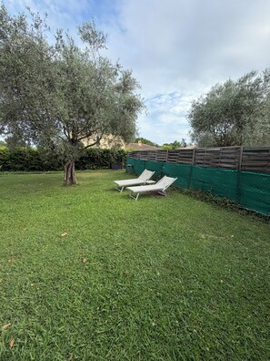 A grassy outdoor area with two white lounge chairs and a tree. - "Gege's Cottage" House with a garden and a pool (Vence)