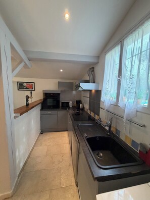 A compact kitchen with a microwave, stove, sink, and a window with curtains. - "Gege's Cottage" House with a garden and a pool (Vence)