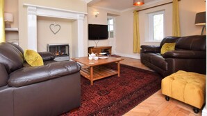 Ein Wohnzimmer mit Kamin, Ledersofas, einem Couchtisch und einem Fernseher.