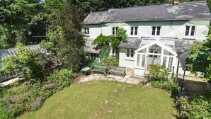 Ein zweistöckiges Haus mit großem Garten, Wintergarten und einem sichtbaren Schornstein.