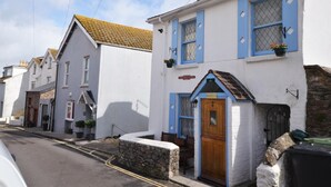 A row of white buildings with blue trim and a stone wall in front. - 1 Bed in Brixham (oc-73940) (Brixham)