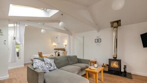 Ein modernes Wohnzimmer mit einer Couch, einem kleinen Tisch, einem Kamin und einem Oberlicht.