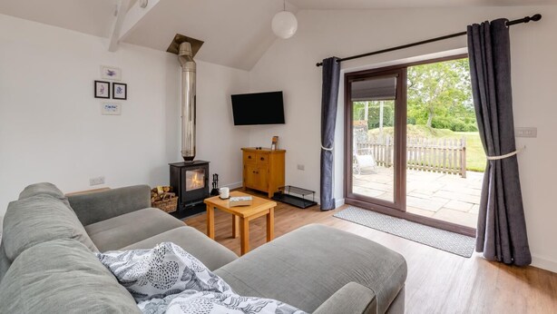 Ein Wohnzimmer mit Sofa, Tisch, Fernseher, Kamin und einer Glastür zum Patio.
