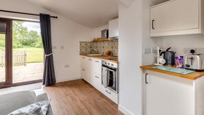 Eine kleine Küche mit einer Holz Arbeitsplatte, weißen Schränken und einer gefliesten Spritzschutzwand.