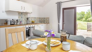 A cozy kitchen with a dining table set for breakfast, a coffee maker, and a view of the garden. - 1 Bed in Taunton (oc-74145) (Williton)