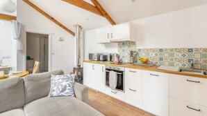 A modern kitchen with white cabinets, a wooden ceiling, and a tiled backsplash. - 1 Bed in Taunton (oc-74145) (Williton)