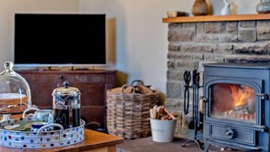 Una sala de estar acogedora con chimenea, televisor y mesa de comedor con una bandeja a lunares.