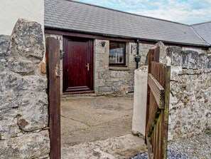 A stone building with a wooden door, a window, and a small porch area. - 1 Bed in Swansea (oc-74221) (Southgate)