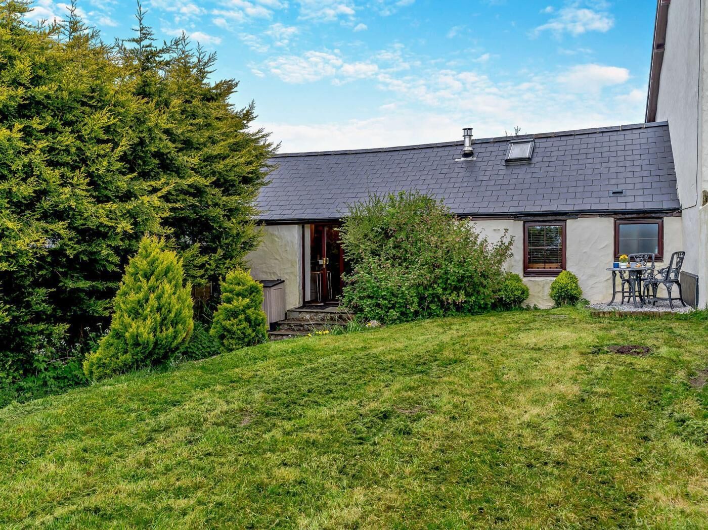 A house with a sloped roof, a front door, and a small patio with outdoor furniture.