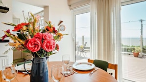 A dining table with a vase of flowers, wine glasses, plates, and cutlery. - 4 Bed in Bridgend (oc-74236) (Ogmore-by-Sea)