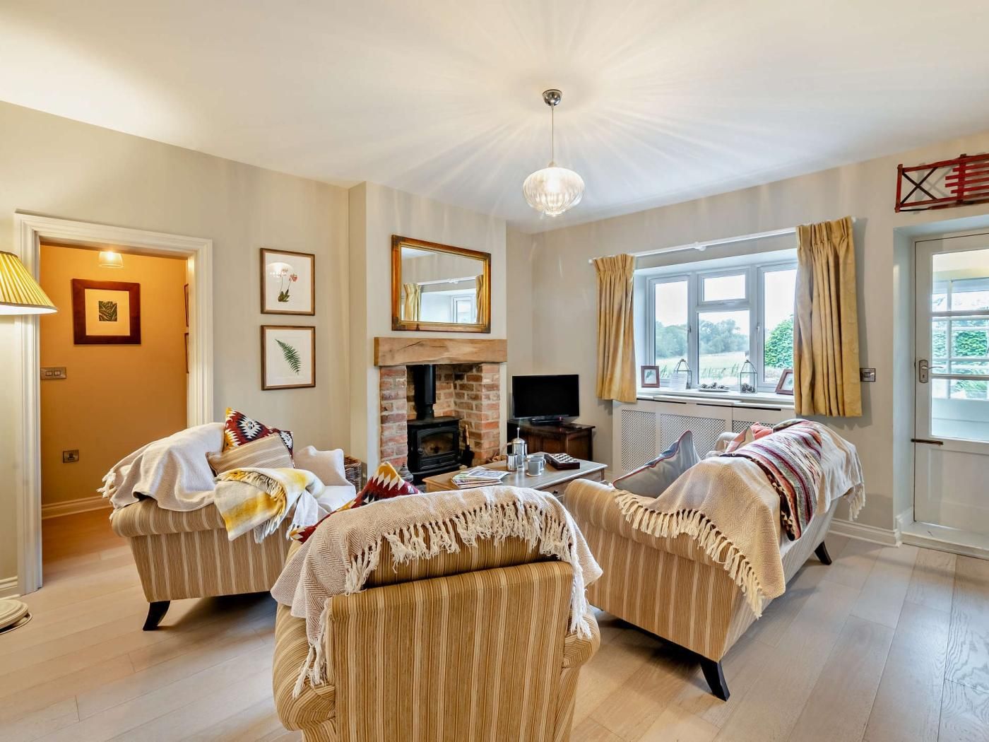 A living room with two sofas, a fireplace, a television, and a window with curtains.