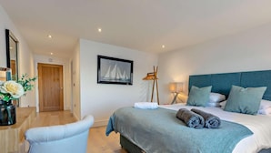 A bedroom with a bed, bedside table, chair, and a painting on the wall. - 3 Bed in Torpoint (oc-74300) (Kingsand)