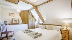 A bedroom with a large bed, wooden beams, a desk, and a chair. - 3 Bed in Dorchester (oc-dc008) (Chaldon Herring)