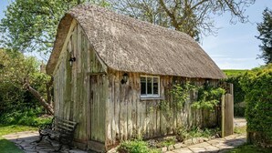 A rustic thatched-roof cottage with a stone pathway leading to the entrance, surrounded by greenery. - 3 Bed in Dorchester (oc-dc008) (Chaldon Herring)