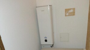 A small room with a beige sofa, a round table, and a white water heater.