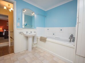 Ein Badezimmer mit einem weißen Waschbecken, einer großen Badewanne und einem Spiegel über dem Waschbecken.